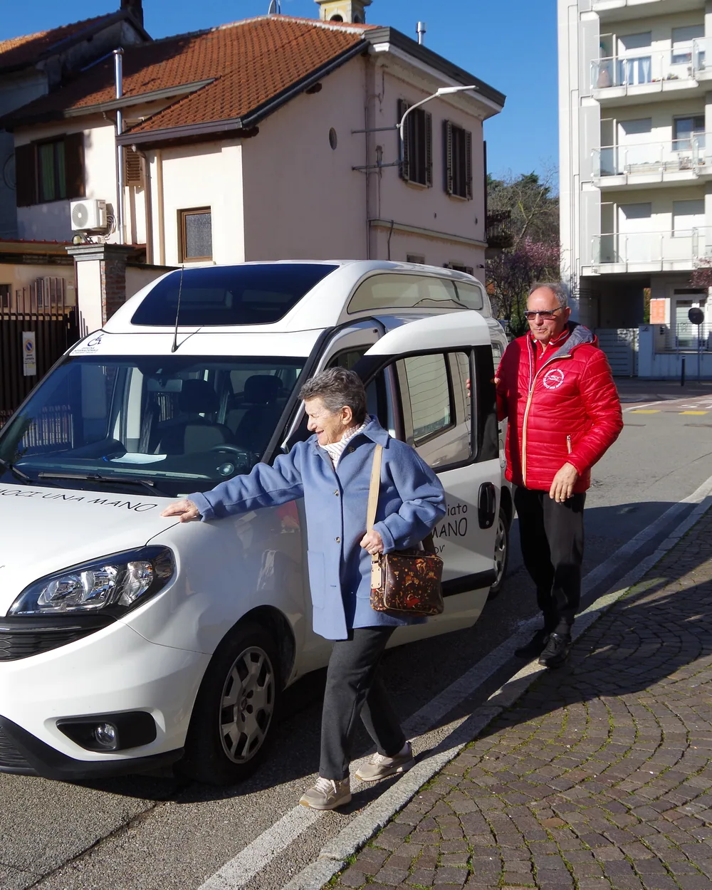 Un volontario e una signora accanto a un mezzo dell’associazione